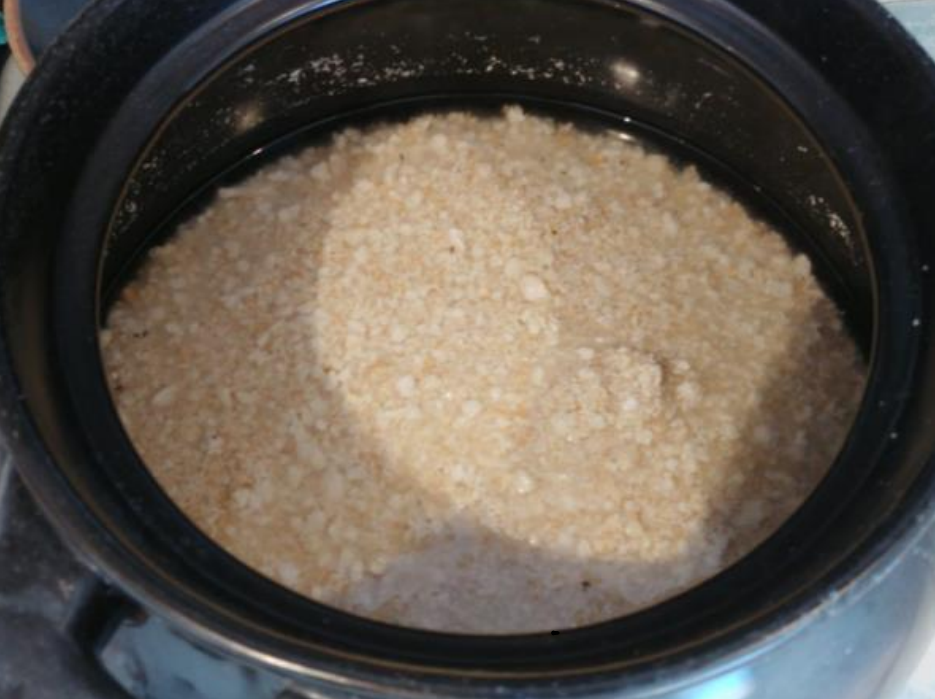 Open black cooking pot containing a granular substance